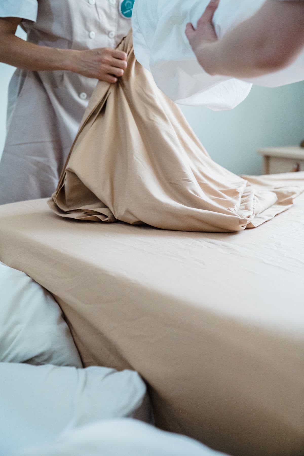 A room mid-turnover, fresh linen going onto the bed